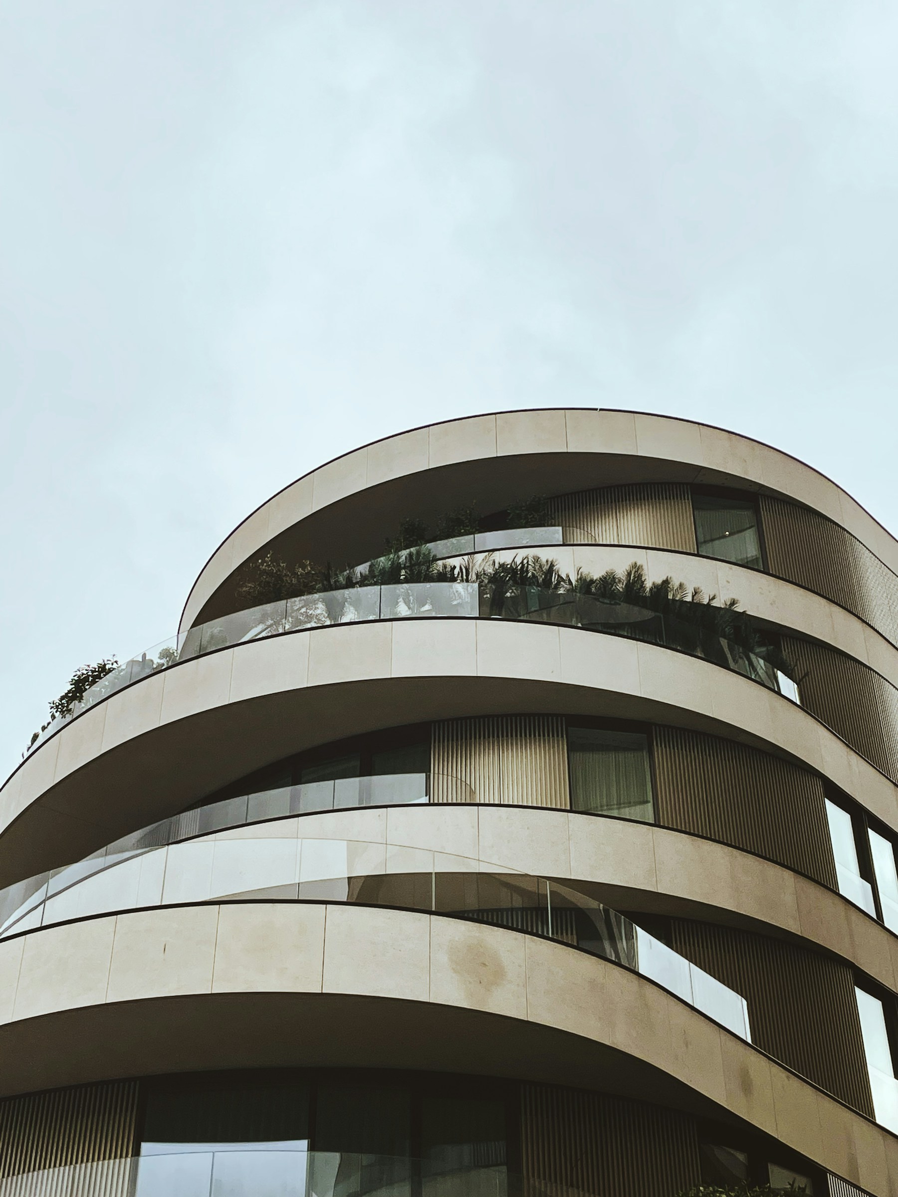 Edificio residencial contemporáneo con balcones curvos, madera y grandes ventanales